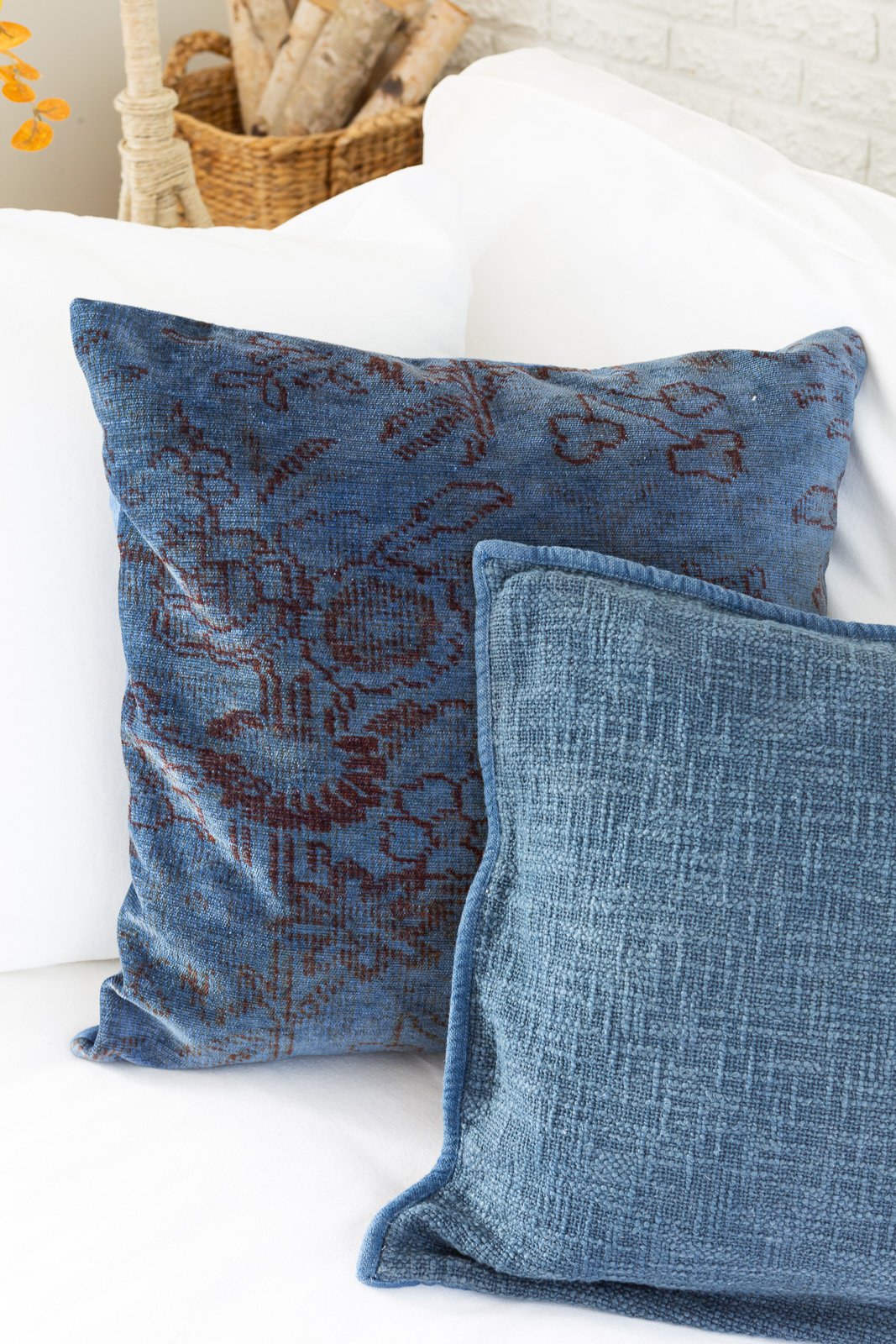 2 dyed denim blue throw pillows on a white sofa